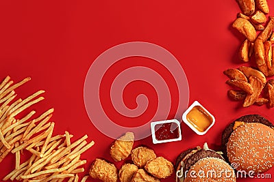Fast food dish top view. Meat burger, potato chips and nuggets on red background. Takeaway composition. Stock Photo