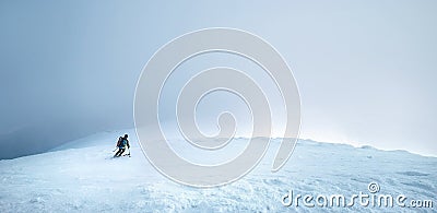 Fast going skier ride down the mountain hill into the storm clouds. Active winter sport concept image Stock Photo