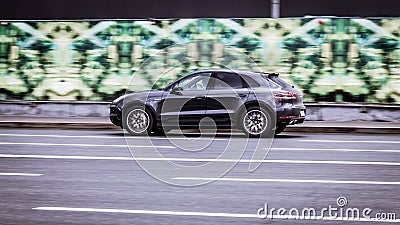 Fast moving white Porsche Macan SUV rides on a city road. A car on street in motion. Overspeed in city concept Editorial Stock Photo