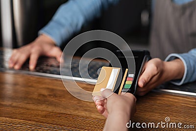 Fast payment for drinks. Girl uses credit card, barman holds terminal on bar counter Stock Photo