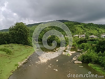 A fast river flowing from the mountains among the stones and a settlement in the mountains Stock Photo