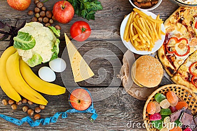 Fastfood and healthy food on old wooden background. Concept choosing correct nutrition or of junk eating. Stock Photo