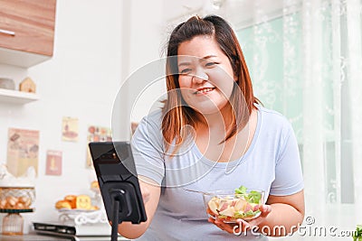 Fat Asian woman cooks organic food in her kitchen at home. Stock Photo