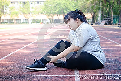 Fat Asian woman injured from jogging Sitting on the floor, holding the right ankle, felt a lot of pain. Stock Photo