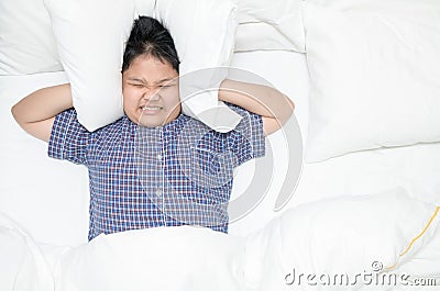 Fat boy covering head with pillow because too loud annoying noise Stock Photo