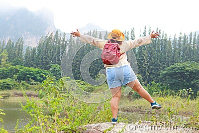 Fat female Asian tourist standing with arms and legs spread. Stock Photo