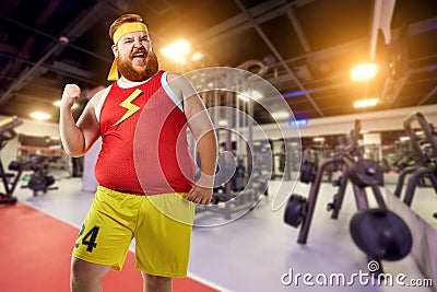 Fat funny man winner smiles in sports clothes in the gym. Stock Photo