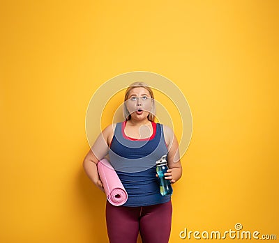 Fat girl does gym at home. surprised expression. Yellow background Stock Photo