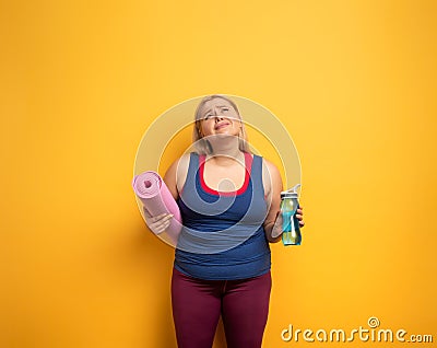 Fat girl does gym at home. tired expression. Yellow background Stock Photo