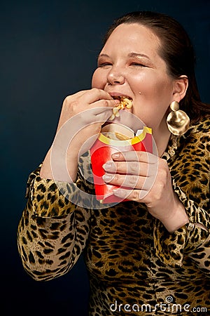 A fat girl is not appetizing, disgusting french fries from a glass. The concept of gluttony. Stock Photo