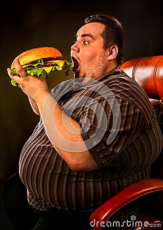 Fat man eating fast food hamberger. Breakfast for overweight person. Stock Photo