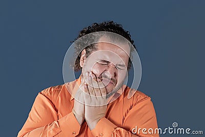 A fat man holds on to his cheek and winces in pain. Toothache and health problems Stock Photo