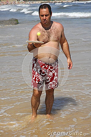 Fat man playing beach tennis on the beach Stock Photo