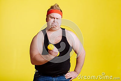 Fat man try to lift small yellow dambbell Stock Photo