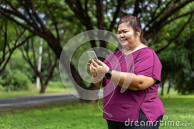 Fat woman asian holding smart phone with listening to music. Stock Photo