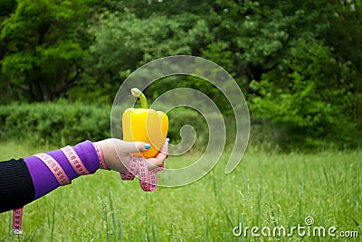 Fat woman close-up in the distance right hand holds a big yellow sweet bell pepper Stock Photo