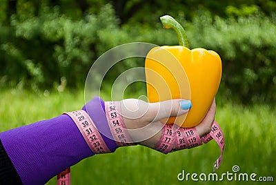 Fat woman close-up in the distance right hand holds a big yellow sweet bell pepper Stock Photo