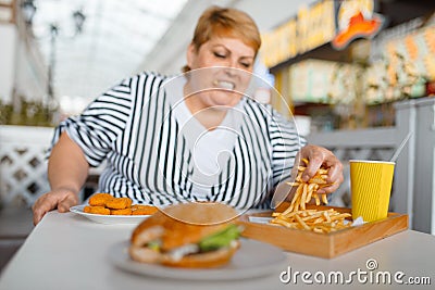 Fat woman eating high calorie food in mall Stock Photo