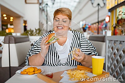 Fat woman eating high calorie food in restaurant Stock Photo