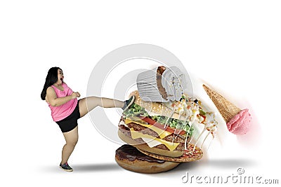 Fat woman kicking tasty foods on studio Stock Photo