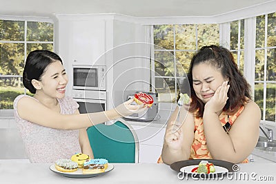 Fat woman rejecting to eat donuts at home Stock Photo