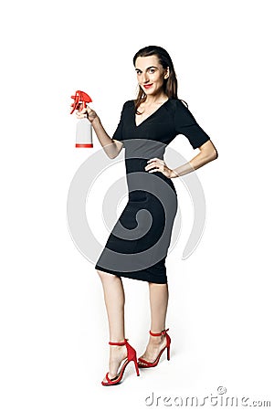 The fatal woman in a black dress with a spray for washing glasses pretending to be a secret agent, holding a spray like a gun. Stock Photo