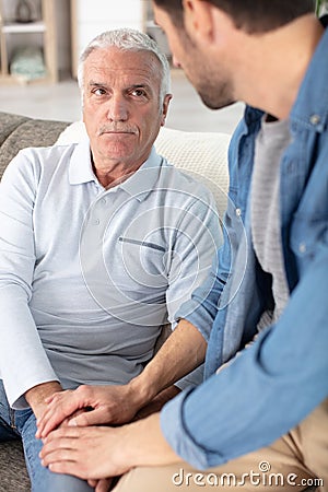 Father and adult son enjoying quiet evening together at home Stock Photo