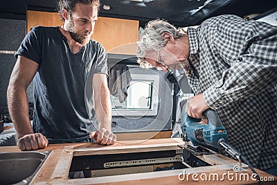 Father and adult son working on the interior of a camper van Stock Photo