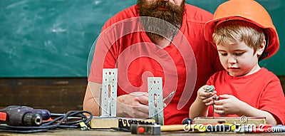 Father as handyman concept. Boy, child in protective helmet makes by hand, repairing, does crafts with dad. Father Stock Photo