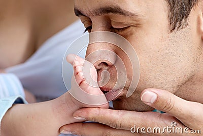 Father of baby kissing a leg Stock Photo