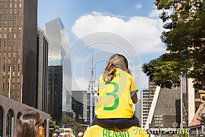 Father carrying his daughter on his shoulders, both wearing green and yellow T-shirts representing the colors of the Brazilian Editorial Stock Photo