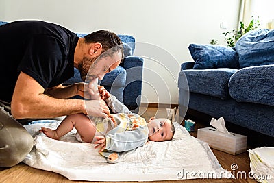 Father changing his baby`s diaper while caressing him affectionately Stock Photo