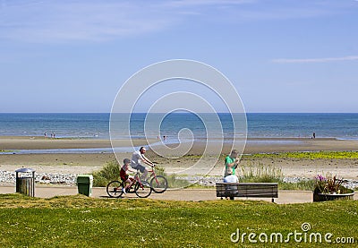 A father and child cycling along the new promenade at Newcastle County Down in Northern ireland on a bright and warm sunny day Editorial Stock Photo