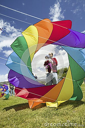 A father and child showing through the center of a rainbow colored kite Editorial Stock Photo