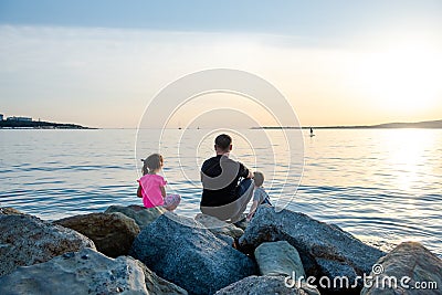 Father with children on a fishing trip by the sea. A boy and a girl with their father have fun fishing on the beach or by the sea. Stock Photo