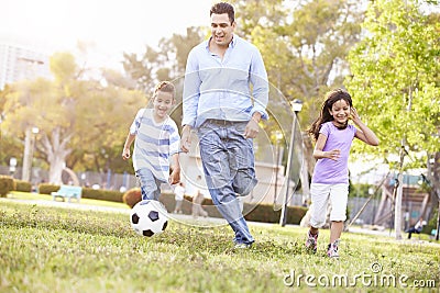 Father With Children Playing Soccer In Park Together Stock Photo