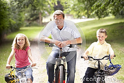 Father and children riding bikes in countryside Stock Photo