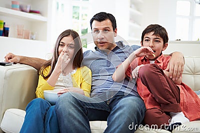 Father And Children Sitting On Sofa Watching TV Together Stock Photo