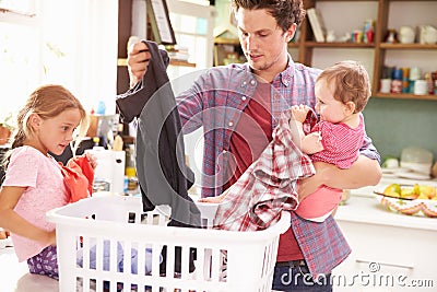 Father And Children Sorting Laundry In Kitchen Stock Photo