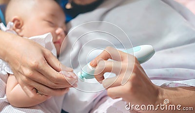 Father cutting my baby`s nails with electic nail clipper while baby sleep Stock Photo