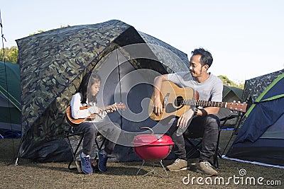 Father and daughter at camping playing ukulele Stock Photo