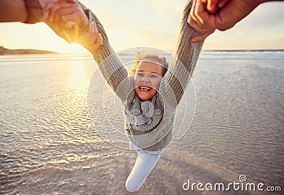 Father and daughter having fun at the beach. Parent swinging little girl around by the arms by the sea at sunset Stock Photo