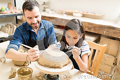 Father And Daughter Making Design On Clay Using Sculpting Tools Stock Photo