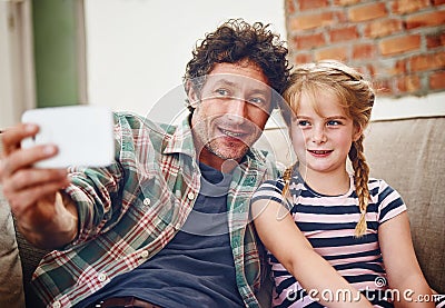 Father and daughter moments to treasure. a father and his little daughter taking a selfie together at home. Stock Photo