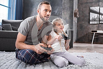 Father and daughter playing with joysticks Stock Photo