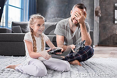 Father and daughter playing with joysticks Stock Photo