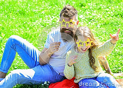 Father and daughter sits on grass at grassplot, green background. Superstar concept. Child and dad posing with star Stock Photo