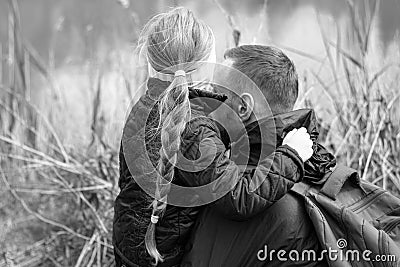 Father and daughter sitting by the lake on the nature lanscape. Little girl with long hair hugging with dad.Father's Day Stock Photo