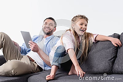 Father with daughter sitting on sofa with digital tablet Stock Photo