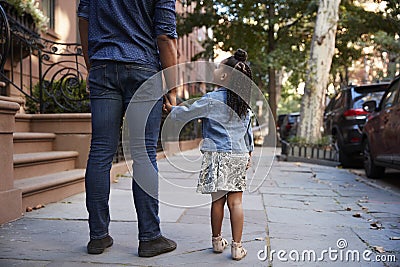 Father and daughter taking a walk down the street, back view Stock Photo